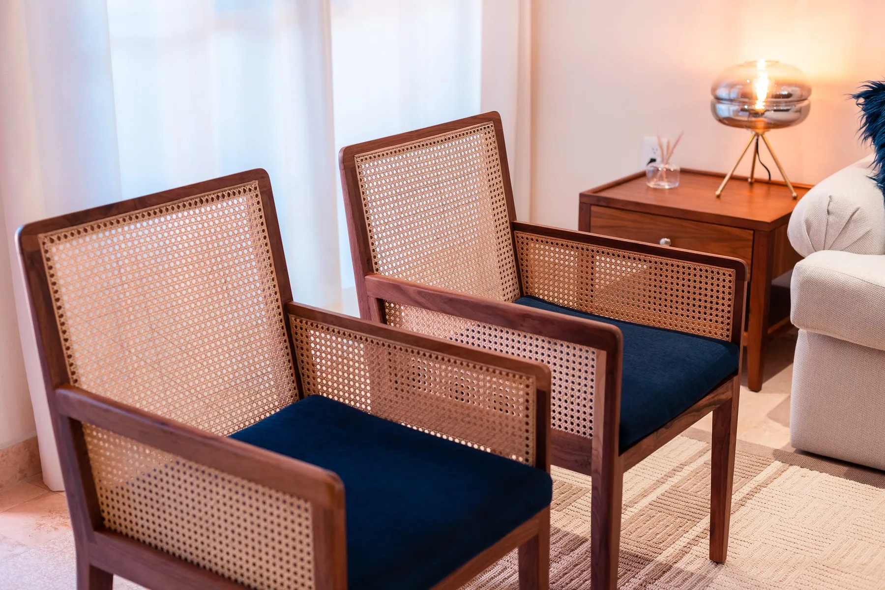 A seating area with two woven-back chairs and a wooden side table.