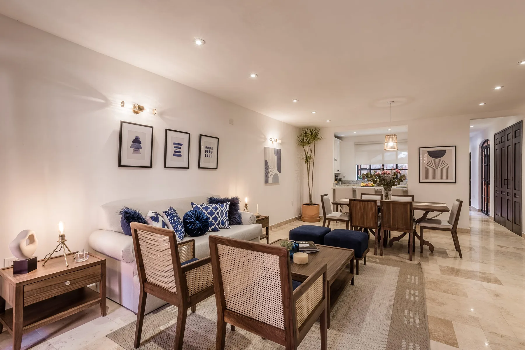 A living and dining area with seating, a dining table, and framed wall art.