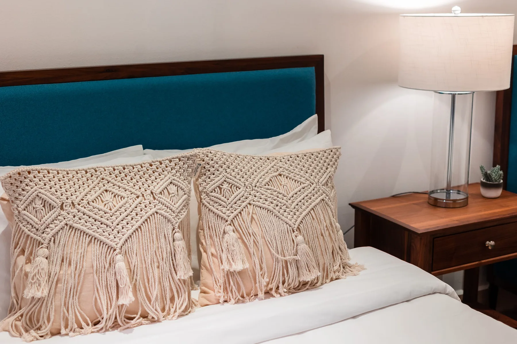 A bedroom with a bed, decorative pillows, and a bedside table with a lamp.