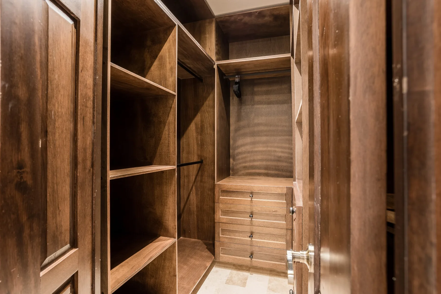 A wooden walk-in closet with open shelving and drawers.