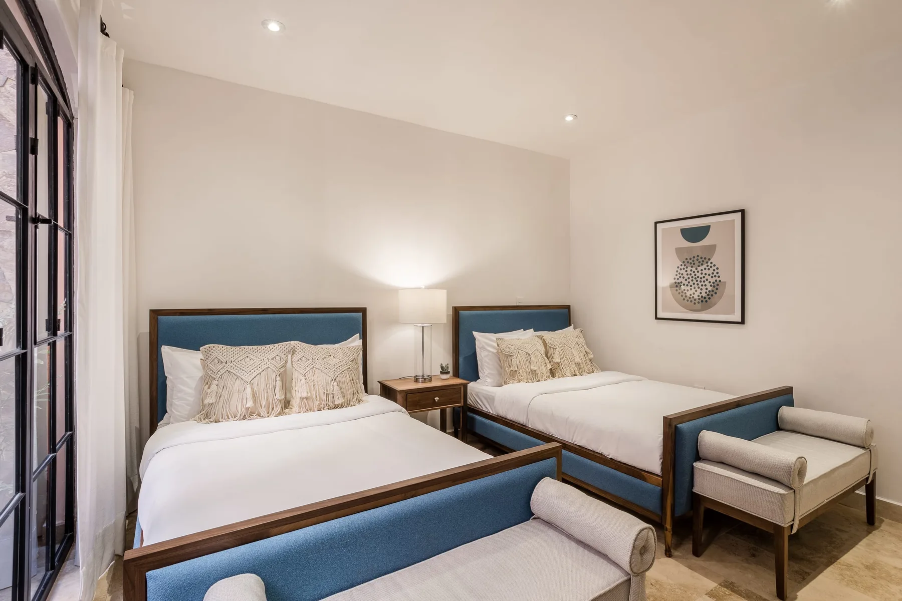 A bedroom with two beds, bedside tables, and a small seating area.