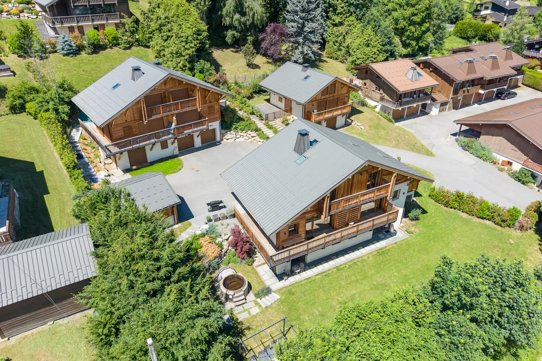 An aerial view shows several wooden houses surrounded by greenery.