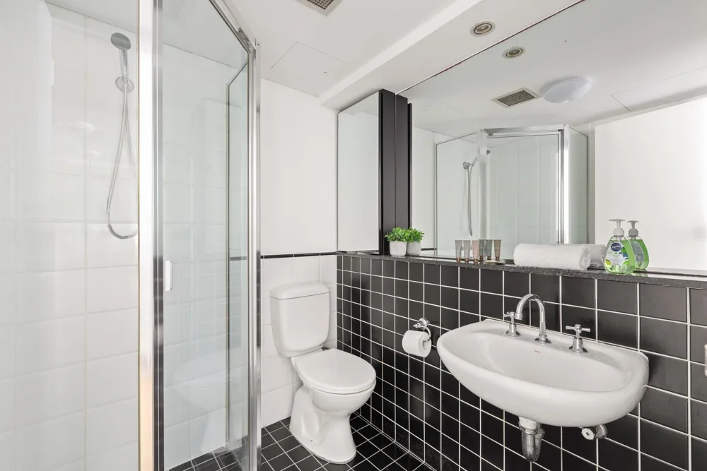 Un baño luminoso con ducha de vidrio, inodoro y lavabo.