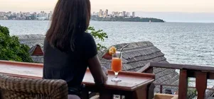 Representative hotel space: A person sits at a wooden table overlooking the water and distant skyline.