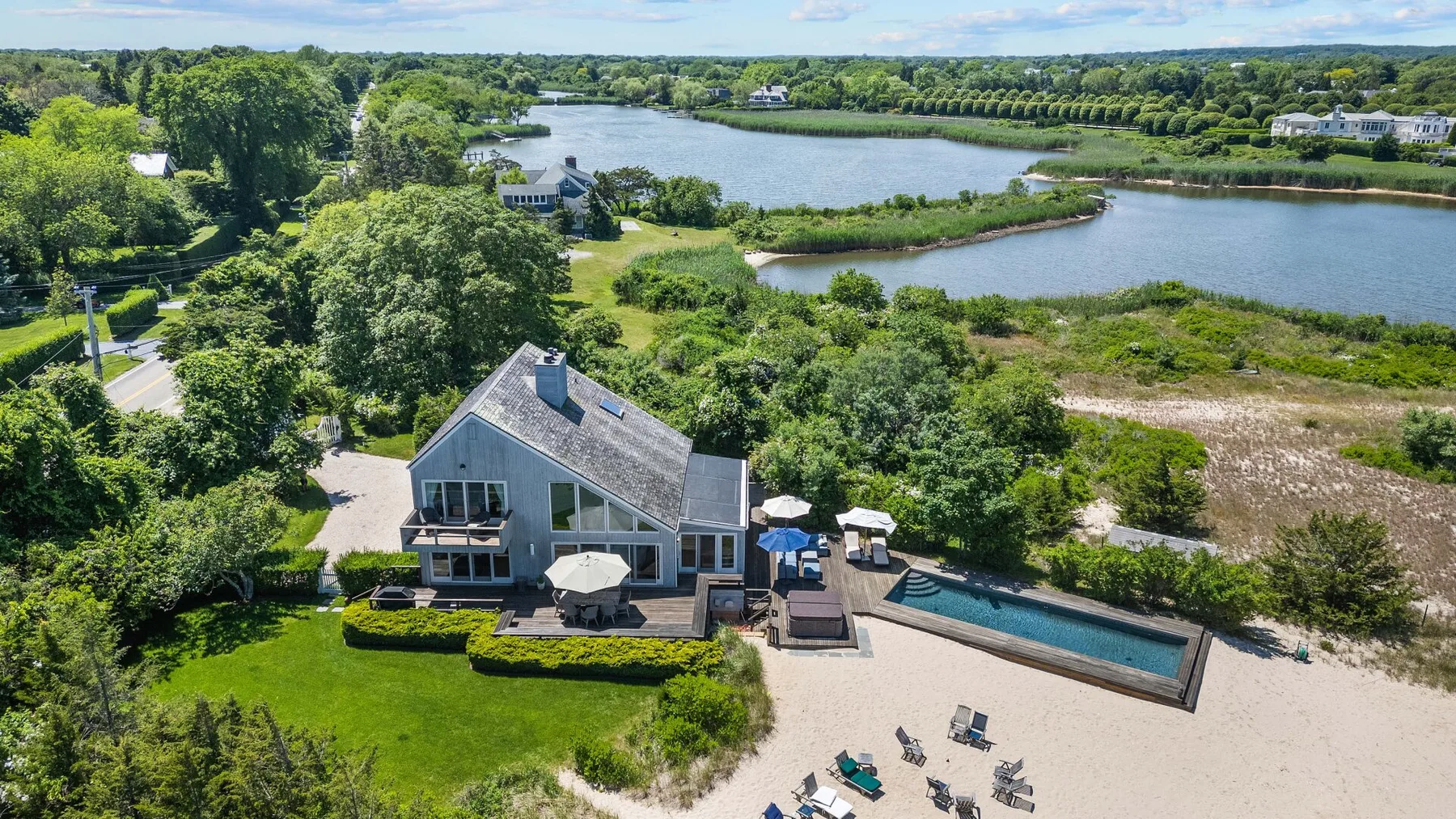 Aerial view of a house beside a pool, patio, and winding waterways.