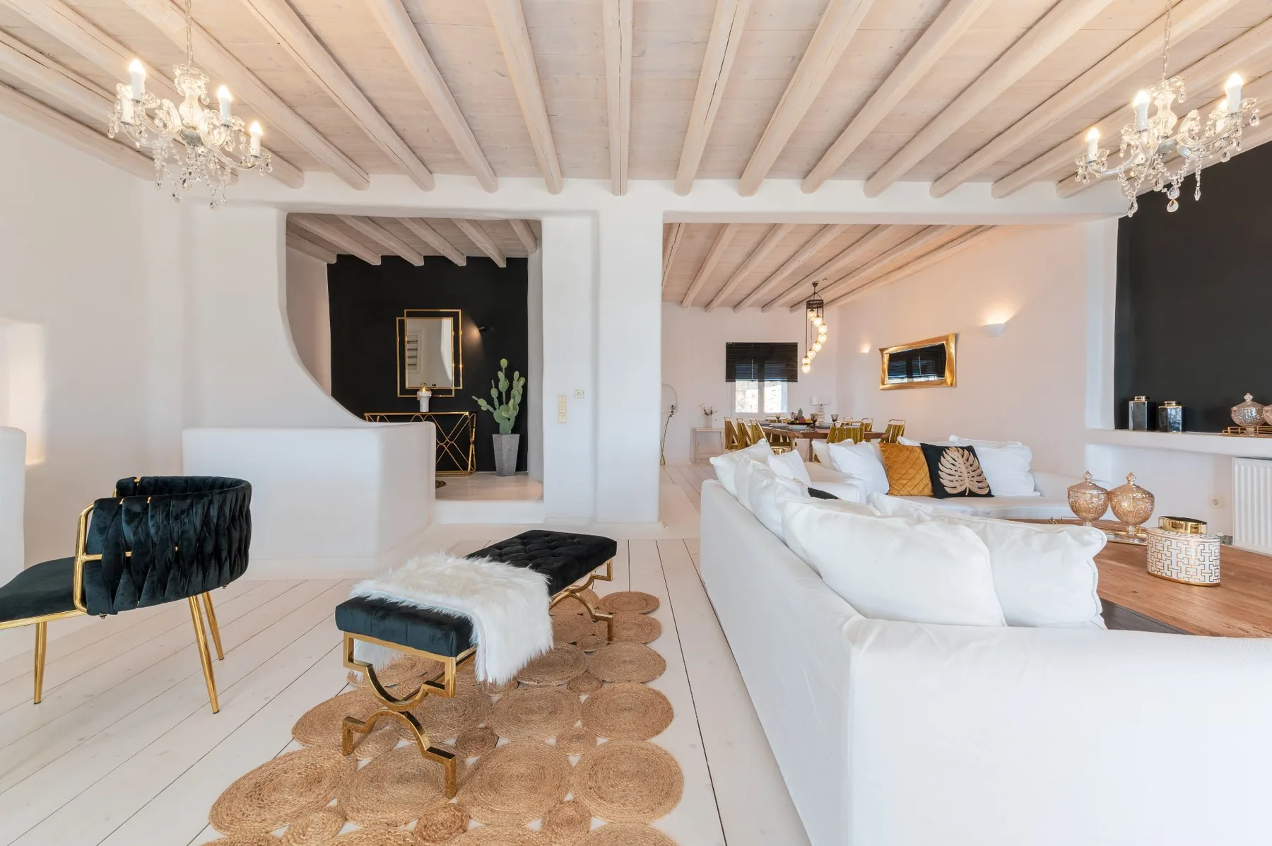 Una sala luminosa con asientos blancos, una mesa baja y vigas expuestas en el techo.