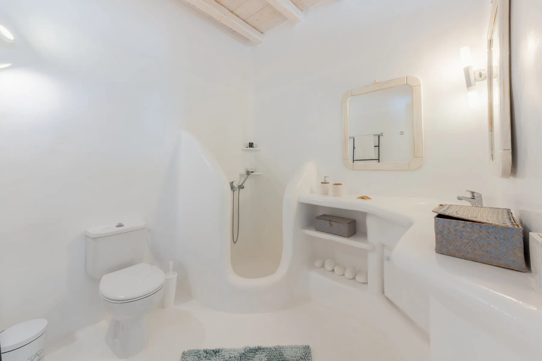 Un baño blanco y luminoso con inodoro, ducha y lavabo.