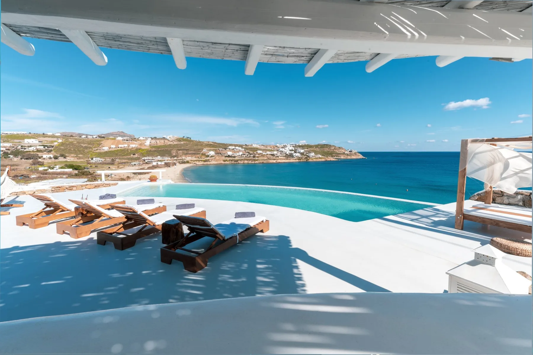 Una terraza con piscina y asientos de descanso da al mar azul.