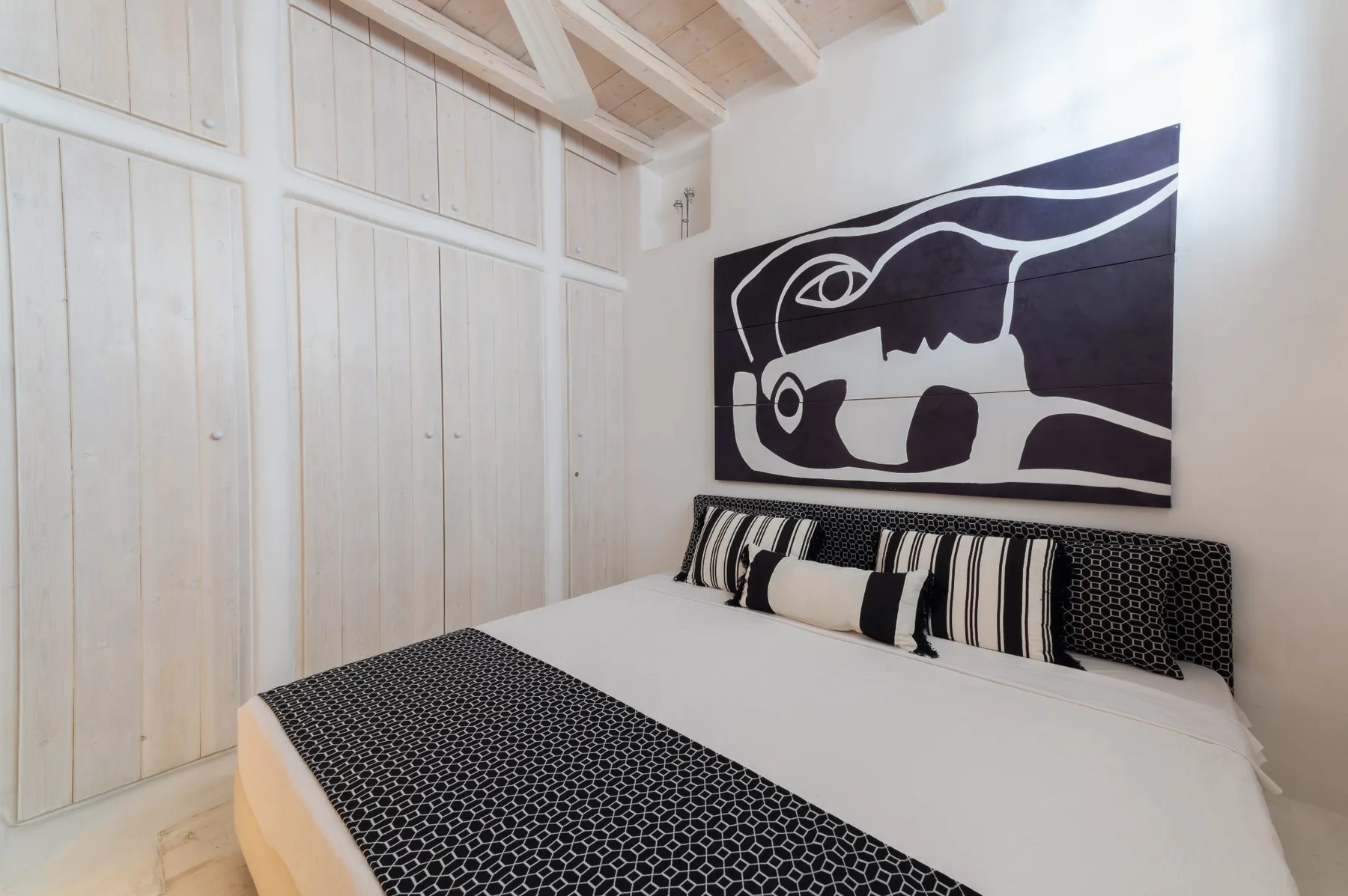 Un dormitorio con una cama bajo una gran obra de arte en blanco y negro.