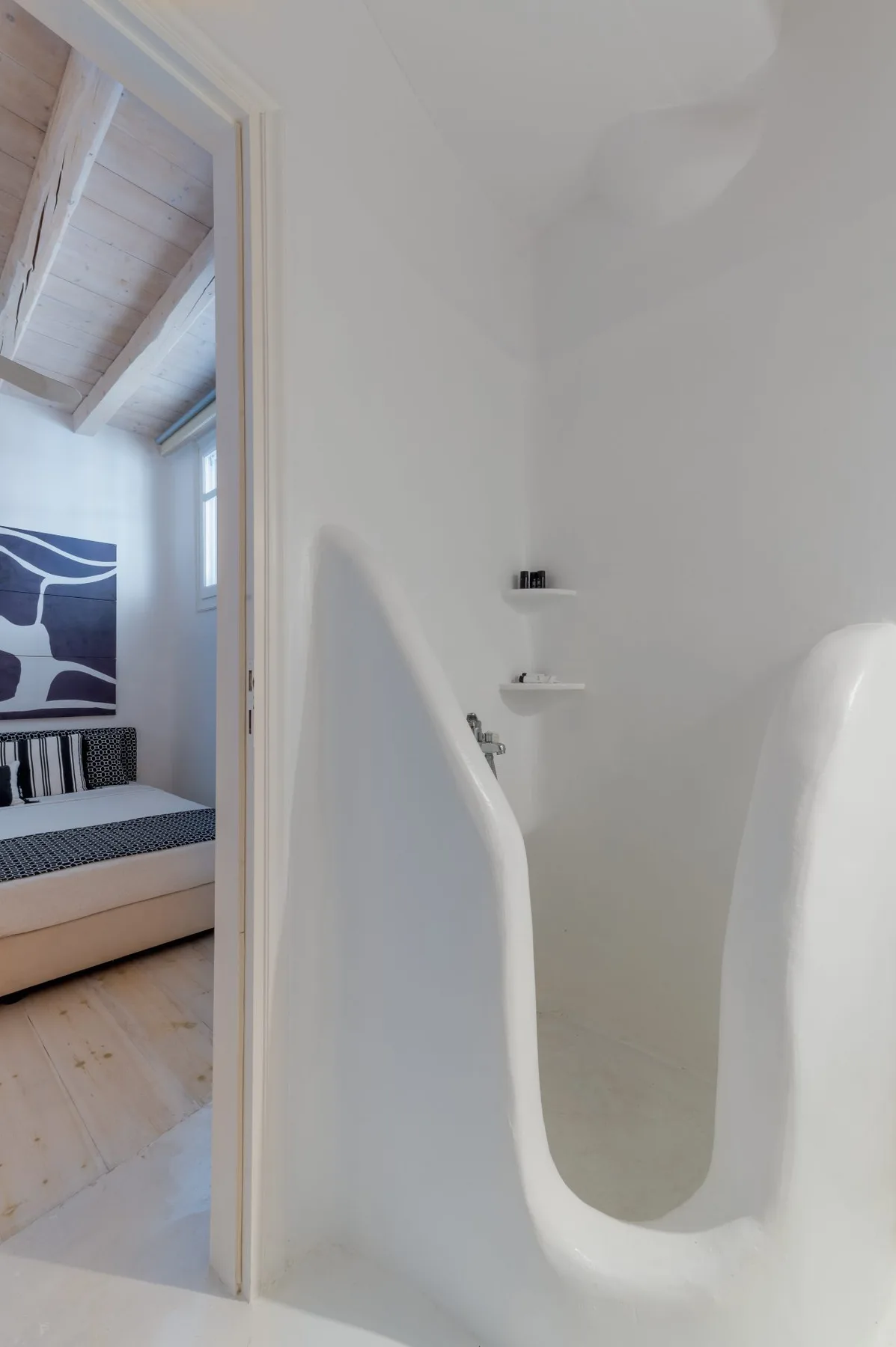 Un baño blanco con una bañera integrada y una puerta abierta a un dormitorio.
