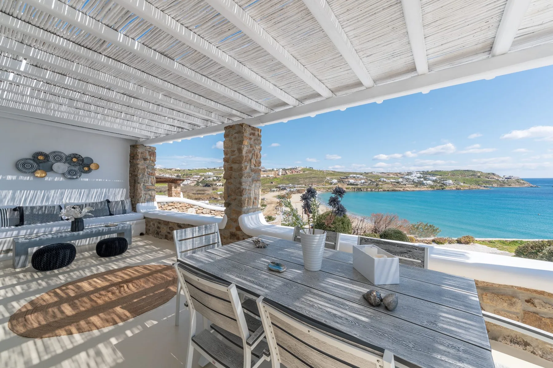Una zona de comedor exterior cubierta tiene vistas al mar, con mesa y asientos.