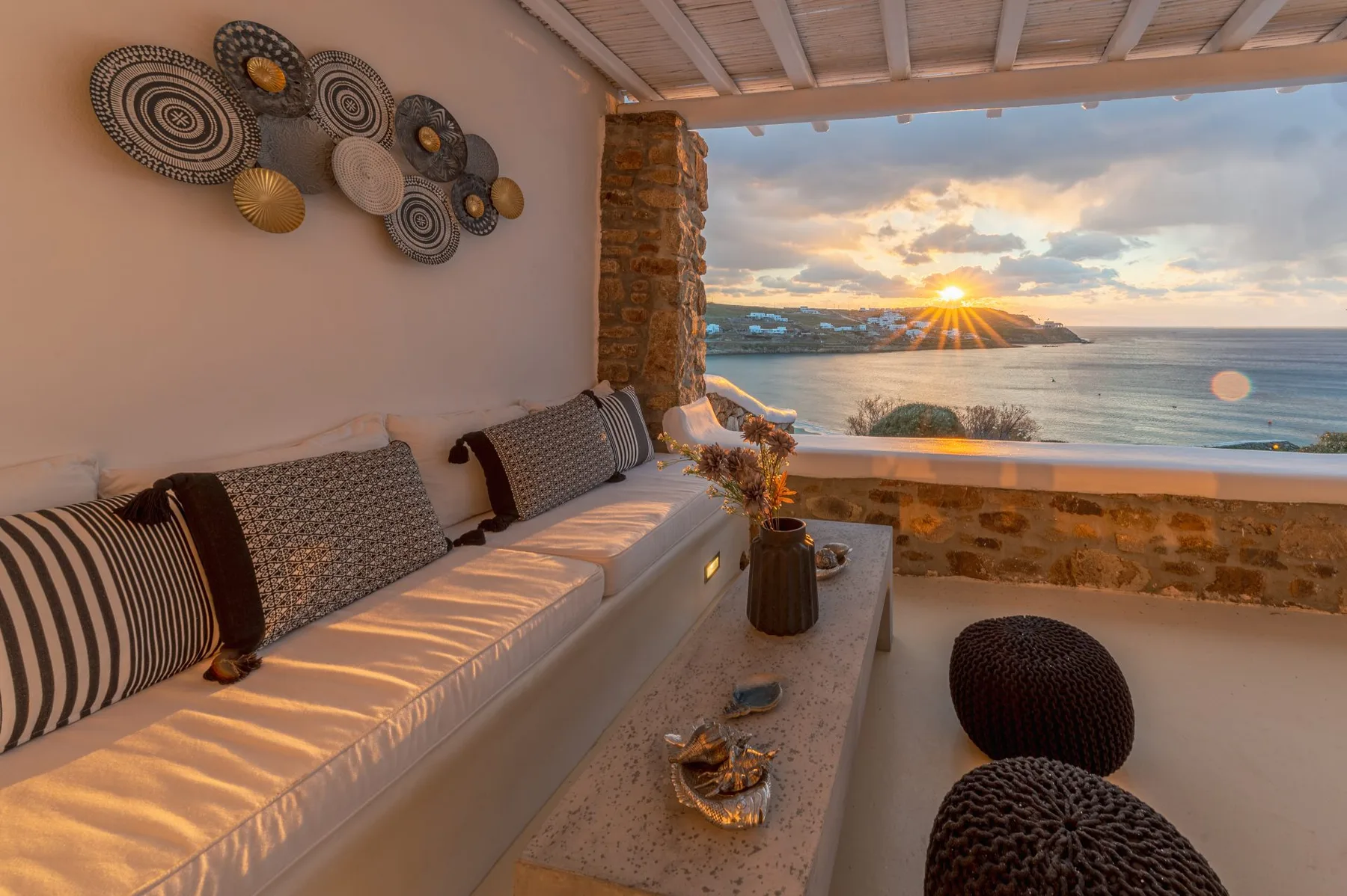 Una zona de estar en una terraza cubierta con vistas al mar al atardecer.