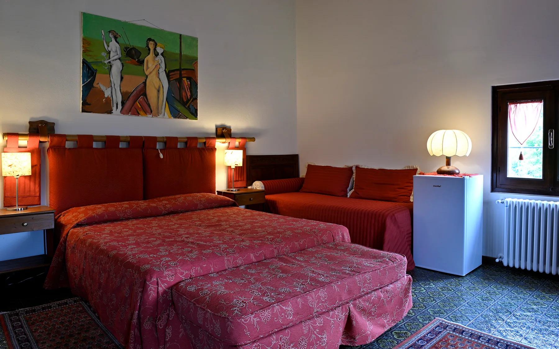 Representative hotel space: A bedroom with red bedding and a small seating area.