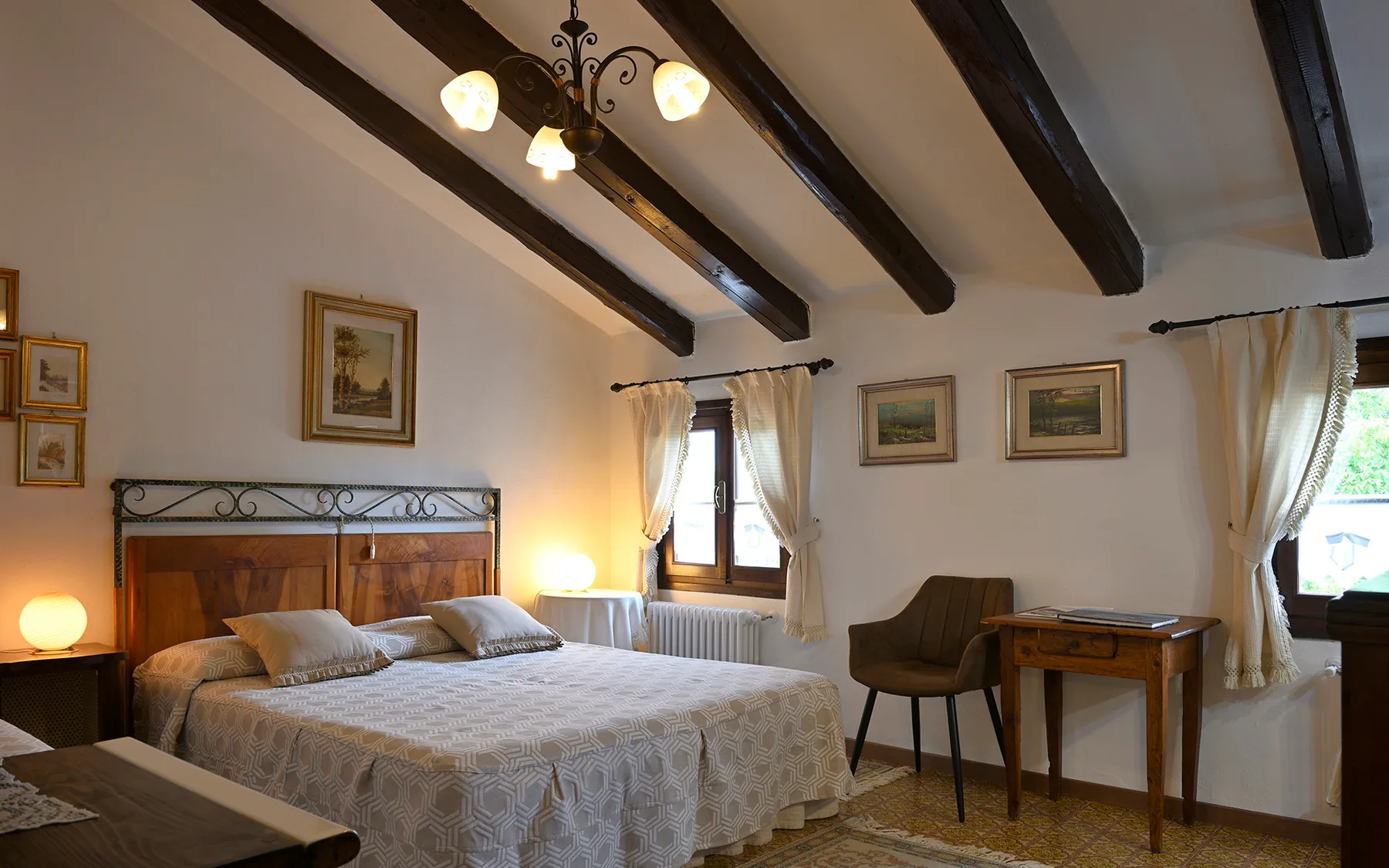 Representative hotel space: A bedroom with a large bed beneath exposed ceiling beams.