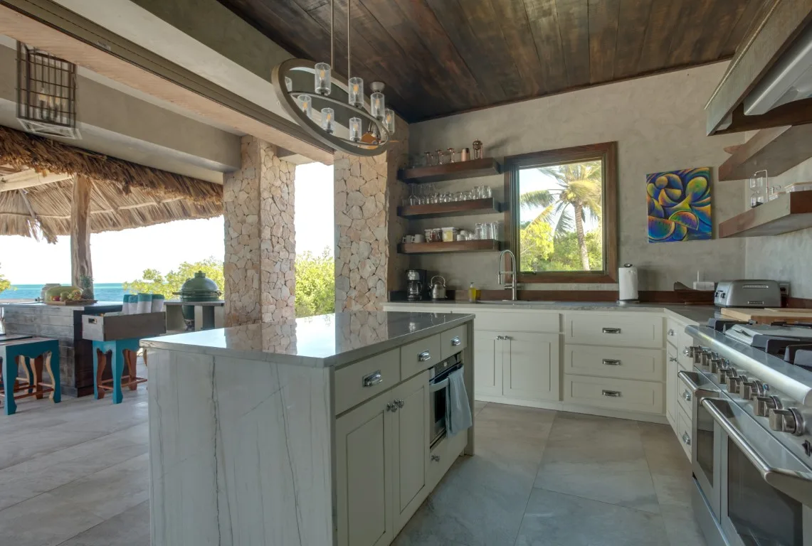 A spacious kitchen with a central island, open shelving, and a dining area by the windows.