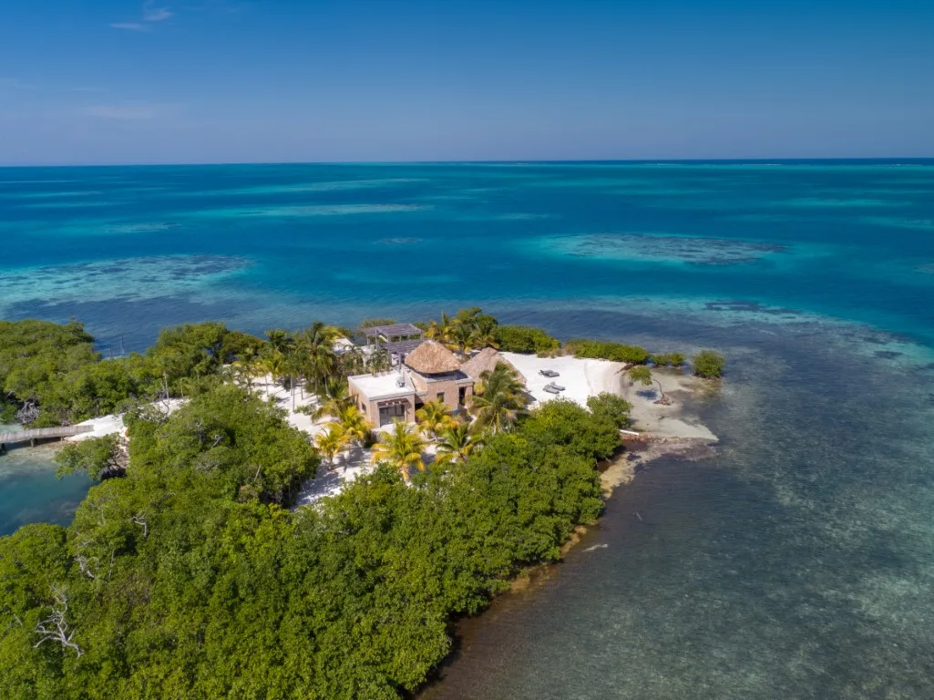 Aerial view of a tropical island resort surrounded by turquoise ocean and green vegetation.