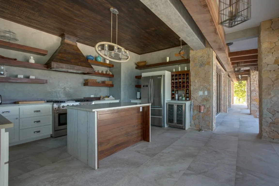 A spacious kitchen with a central island and a stone corridor.