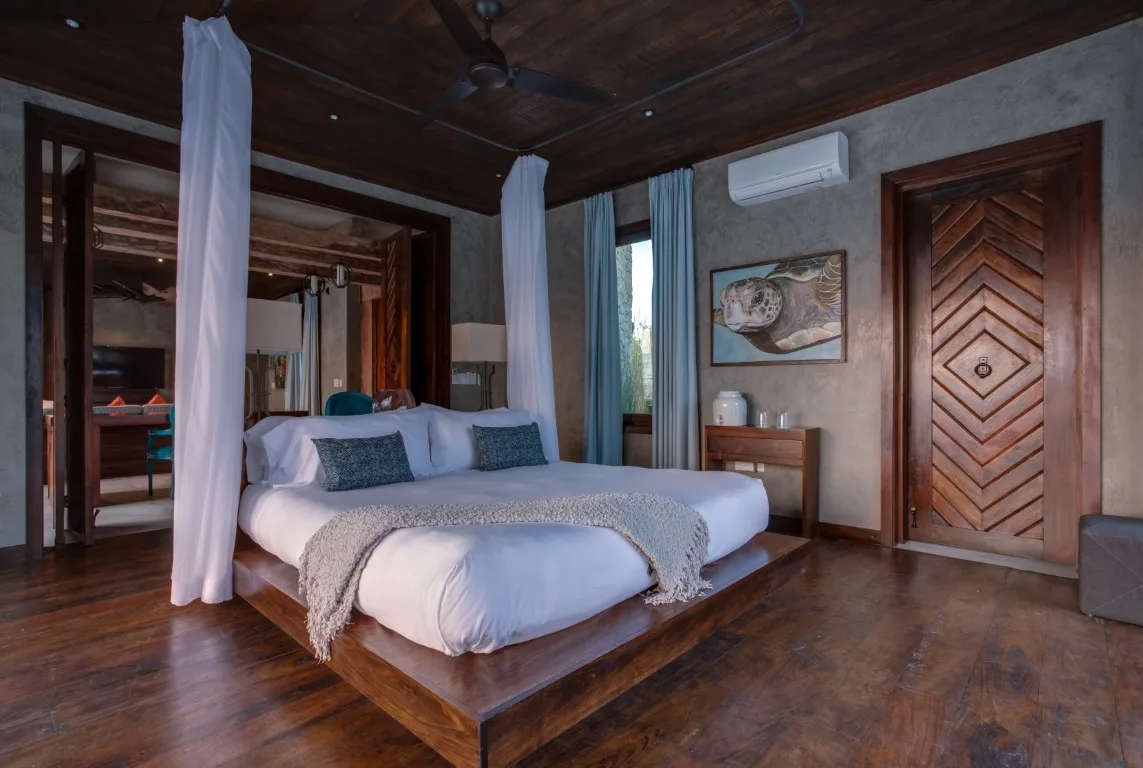 A bedroom with a large bed, white linens, and curtains around the sleeping area.