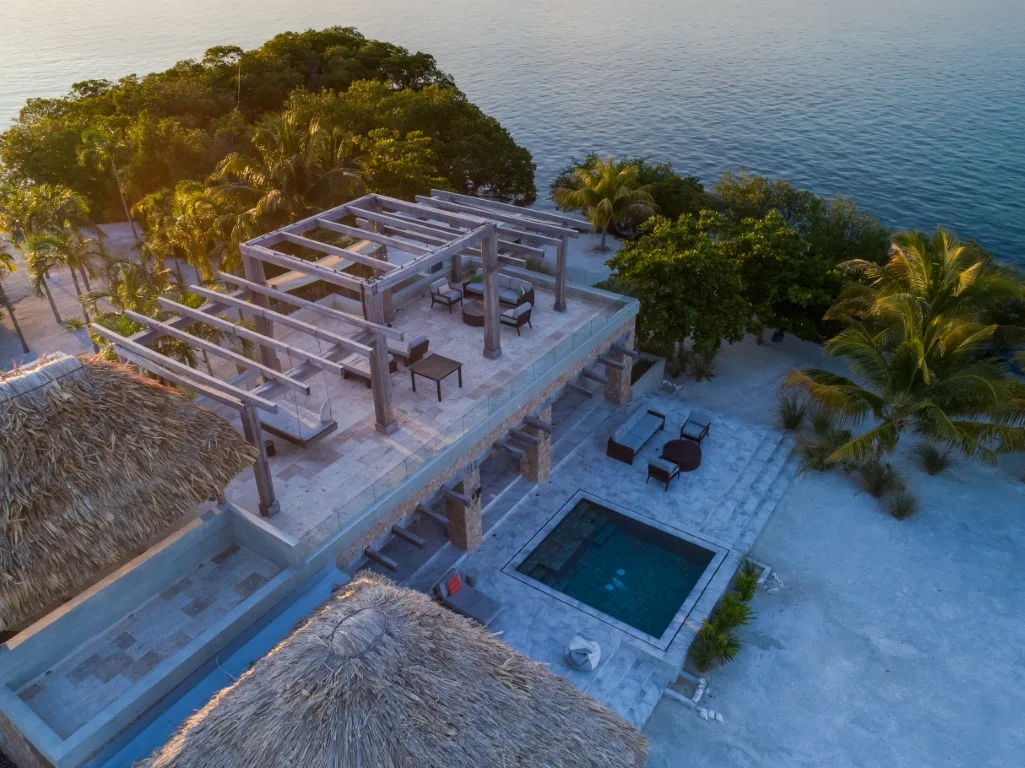 An aerial view of a seaside resort with a rooftop terrace and pool.