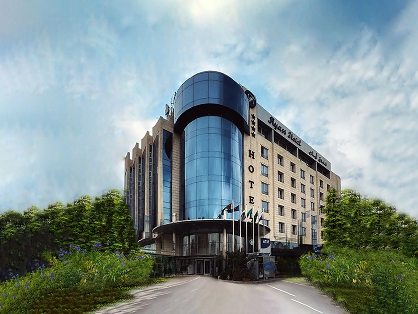 Espacio representativo del hotel: Un edificio de hotel con una fachada curva de vidrio se alza junto a una entrada ajardinada.