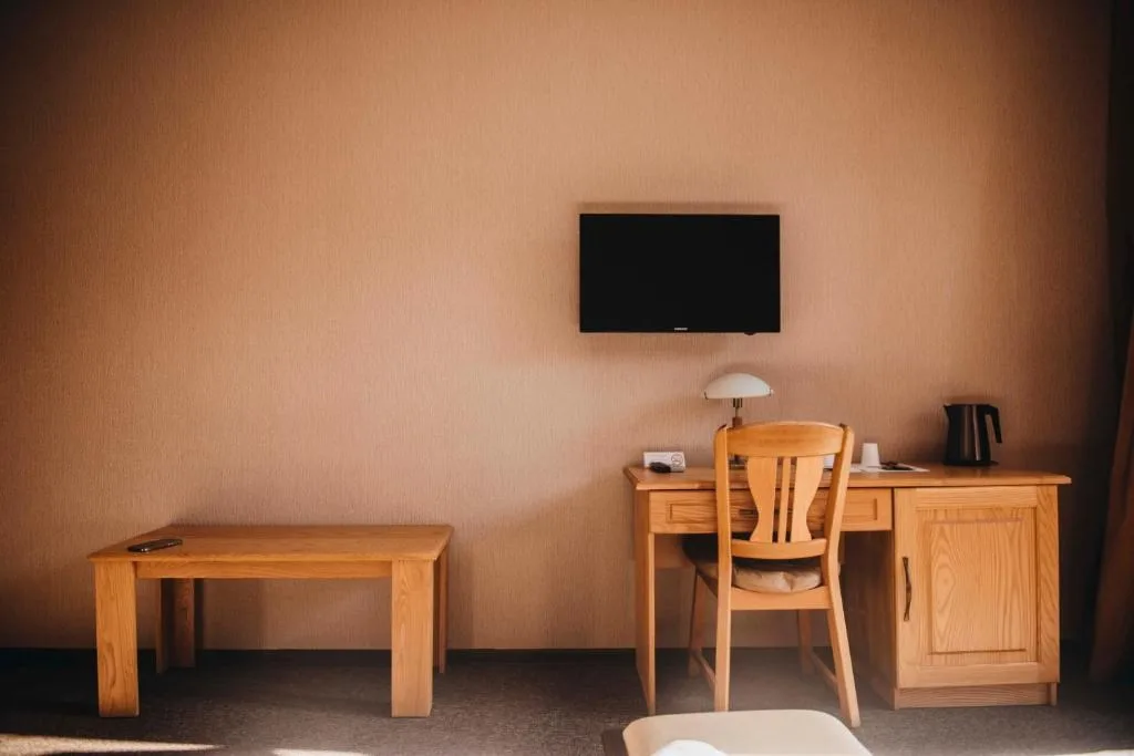 Representative hotel space: A room with a wooden desk and chair beneath a wall-mounted television.