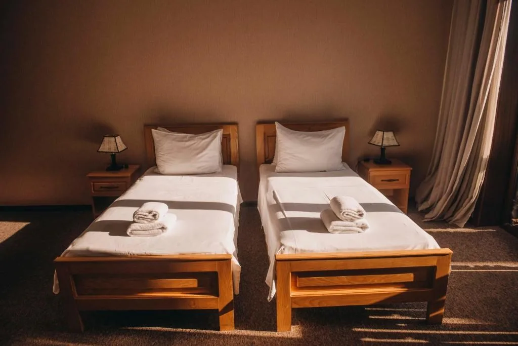 Representative hotel space: A bedroom with two single beds, bedside tables, and lamps.