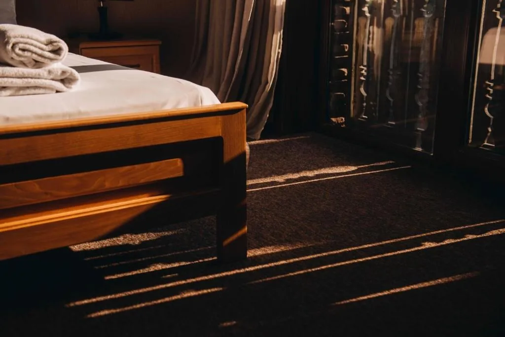 Representative hotel space: A bedroom with a bed and folded towels beside a curtained window.