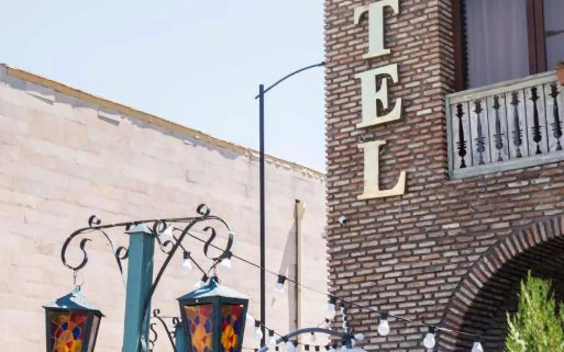 Representative hotel space: A brick hotel facade with a decorative sign and hanging lanterns.