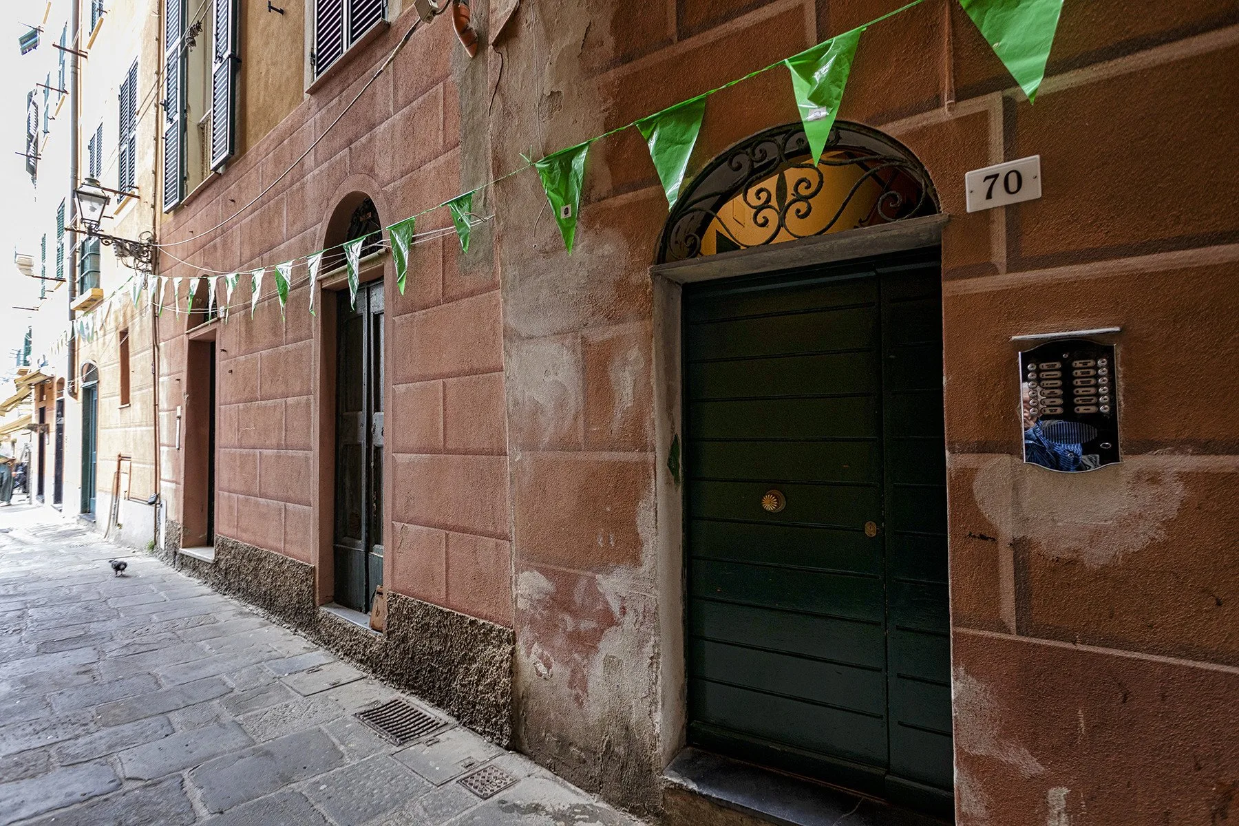 Zona común: Una calle estrecha pavimentada bordea un edificio de piedra con una entrada oscura.