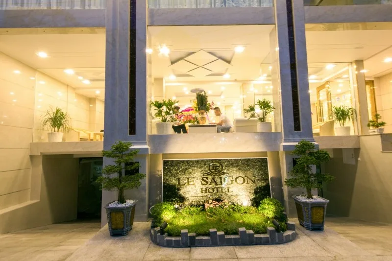 Espacio representativo del hotel: Entrada del hotel con un jardín y un letrero iluminado.