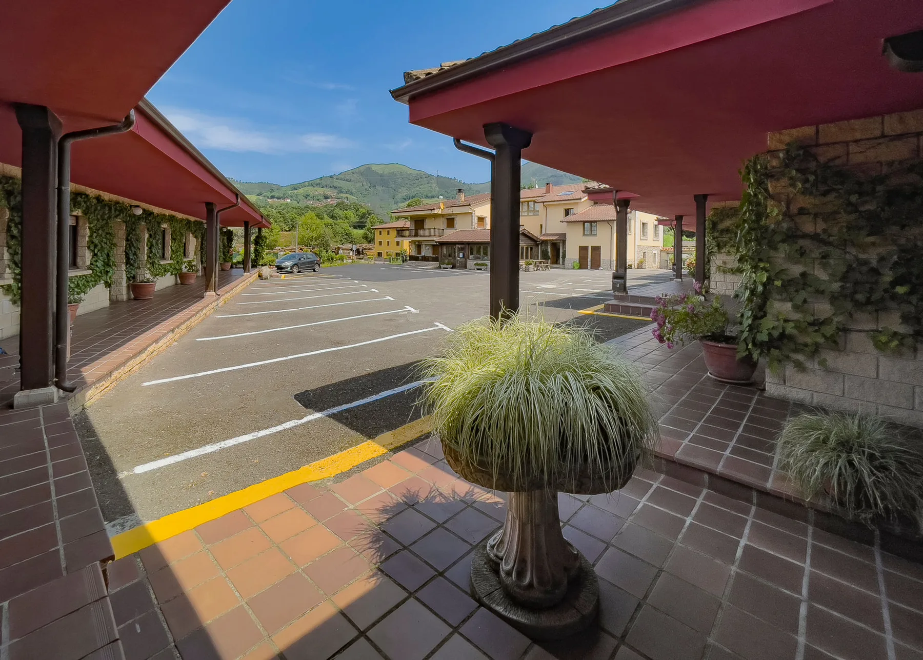 Representative hotel space: A covered parking area with painted spaces and potted plants.
