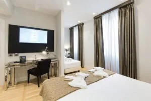 Representative hotel space: A bedroom with a desk and television beside the bed.