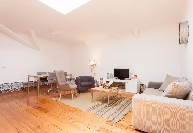A bright living room with seating, a coffee table, and a television.