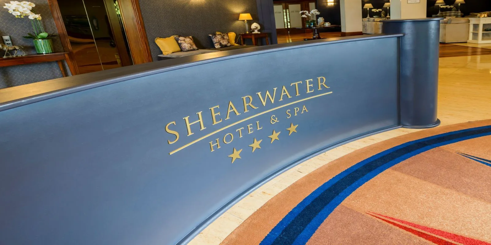 Representative hotel space: A hotel reception desk with a blue front and seating behind it.