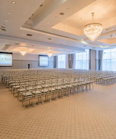 Representative hotel space: A large event hall is arranged with rows of seating beneath chandeliers.