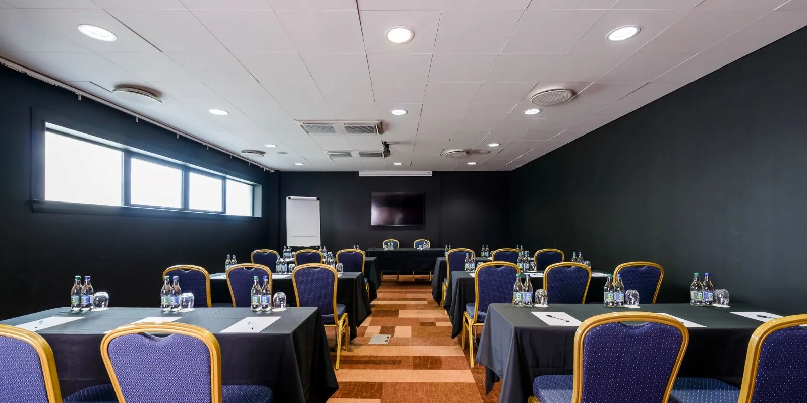 Representative hotel space: A conference room with rows of tables and chairs facing a screen.
