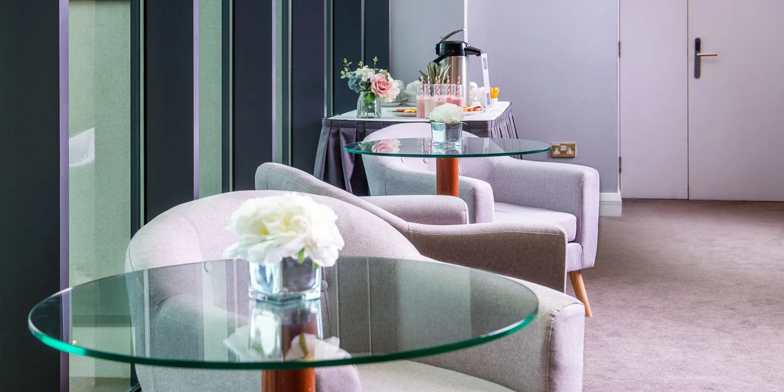 Representative hotel space: A sitting area with upholstered seating, glass tables, and flowers.