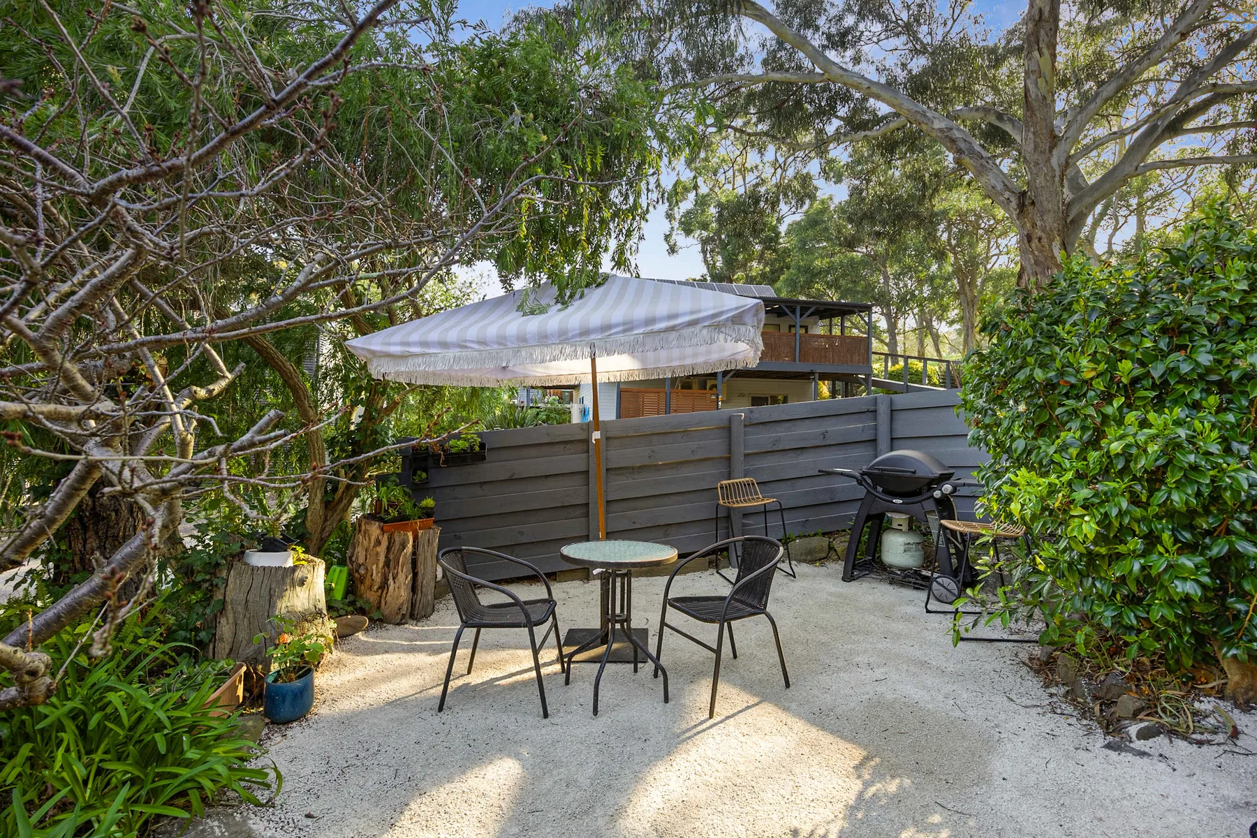 An outdoor patio with a round table, seating, and a large umbrella.