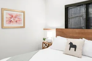 Representative hotel space: A bedroom with white bedding, a wooden headboard, and a framed wall picture.
