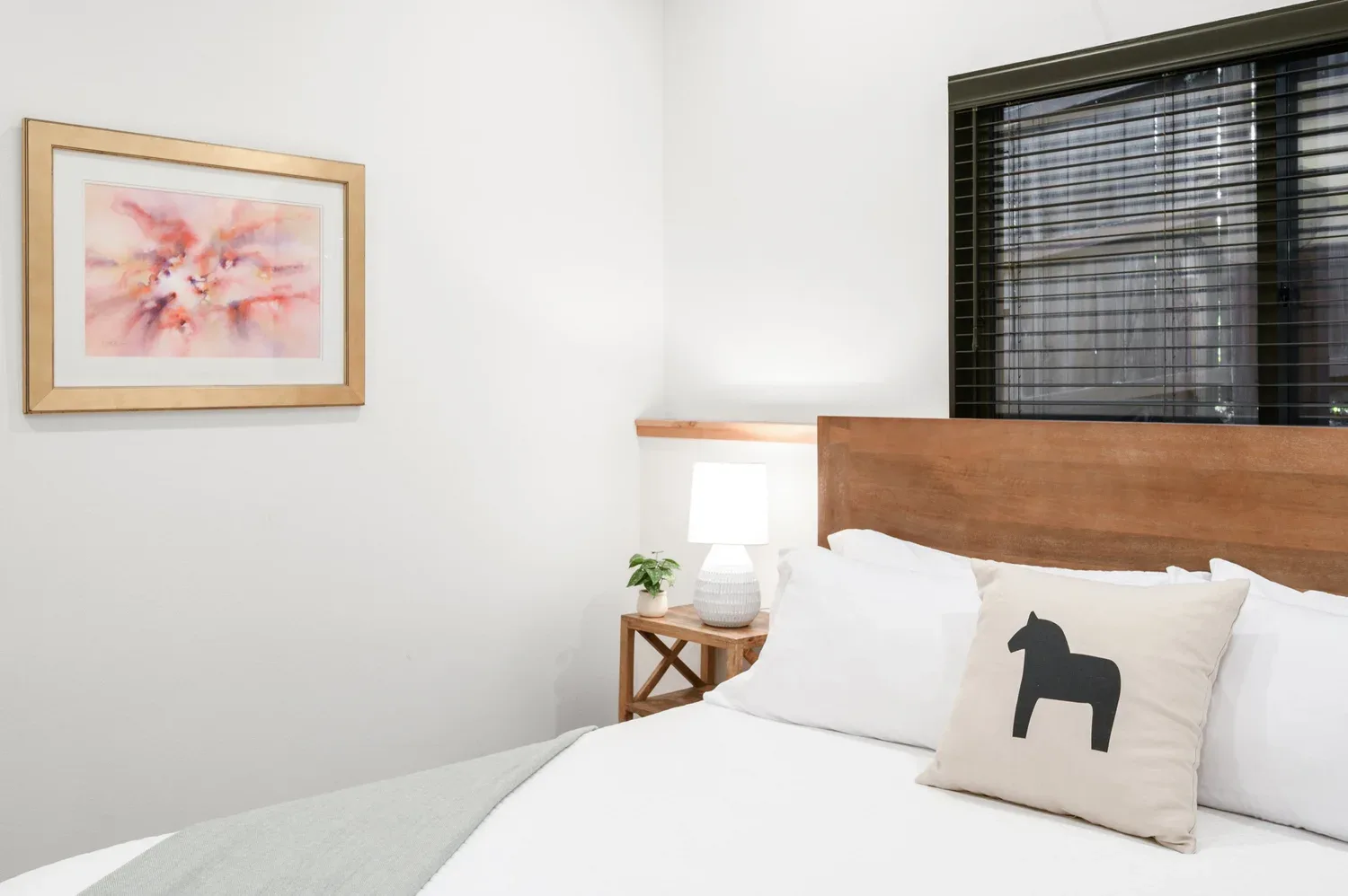 Representative hotel space: A bedroom with a neatly made bed, bedside table, and framed artwork.