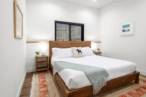 Representative hotel space: A bedroom with a bed, bedside tables, and a window with blinds.