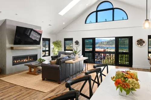 Representative hotel space: A bright living room with seating, a fireplace, and large windows overlooking the water.