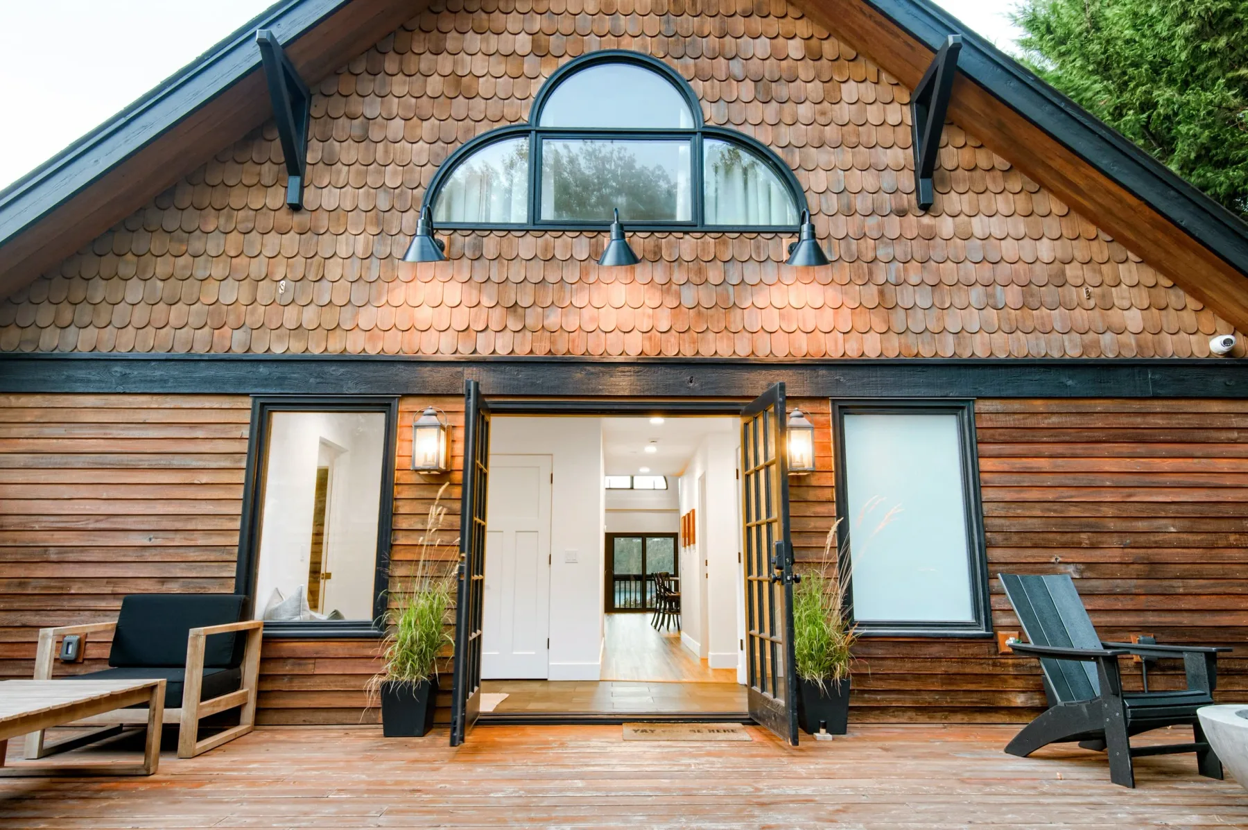 Representative hotel space: A wooden building entrance opens onto a bright interior, with outdoor seating on the deck.