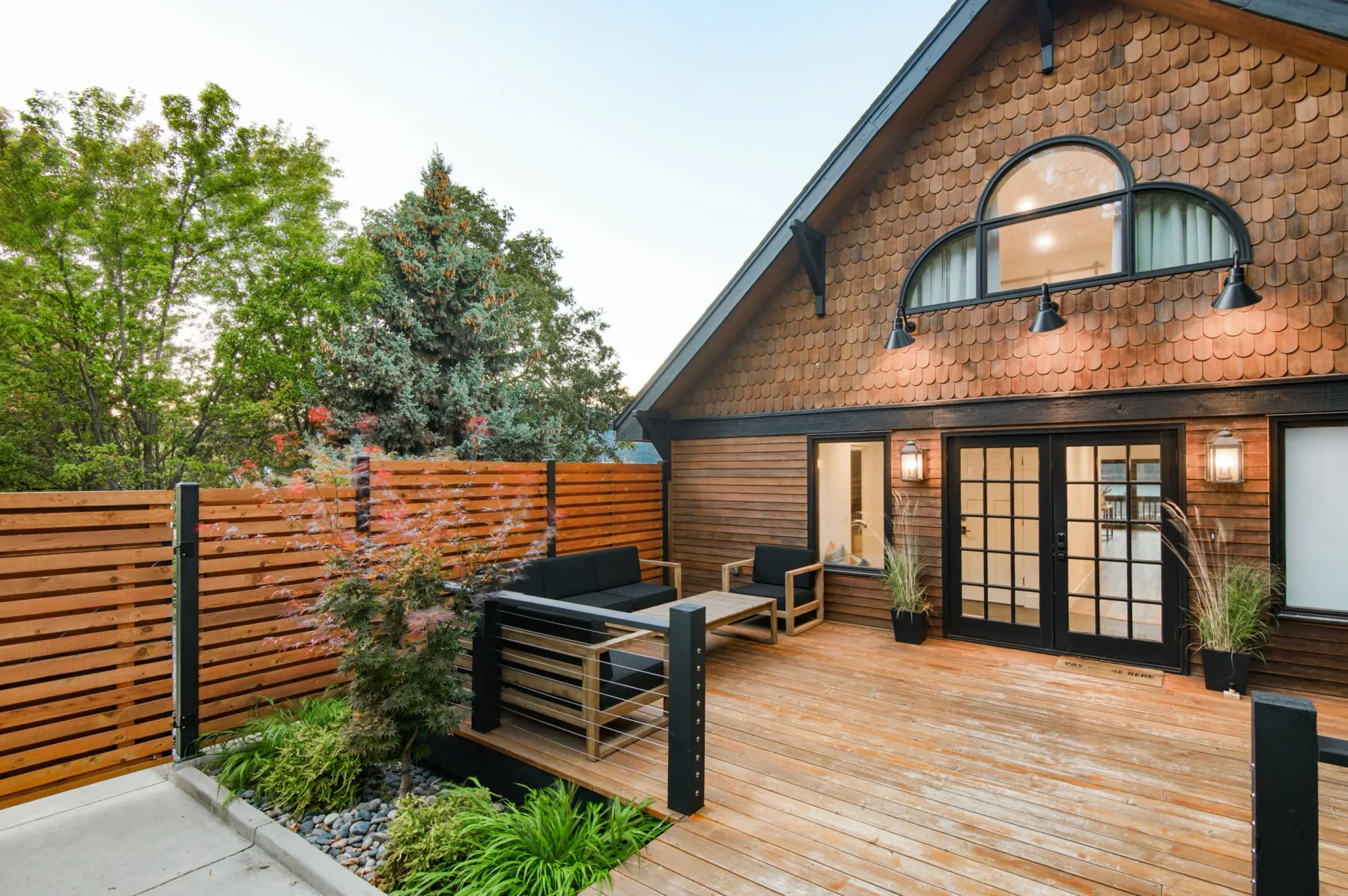 Representative hotel space: A wooden deck with outdoor seating sits beside a timber-clad building.