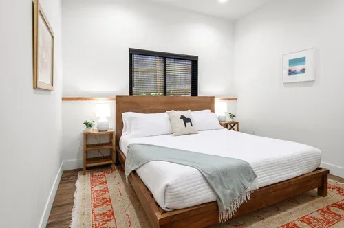 Representative hotel space: A bright bedroom with a wooden bed and a window behind the headboard.