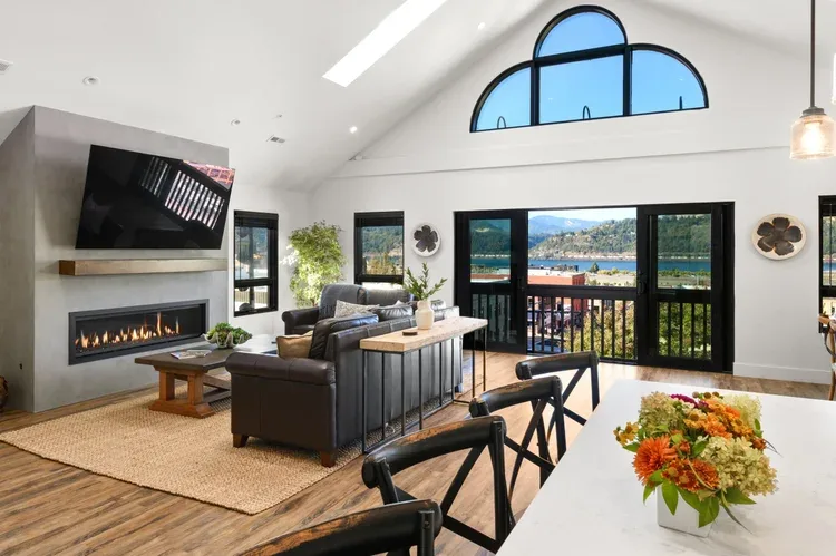 Representative hotel space: A bright living and dining area opens onto a balcony with views of the water and hills.