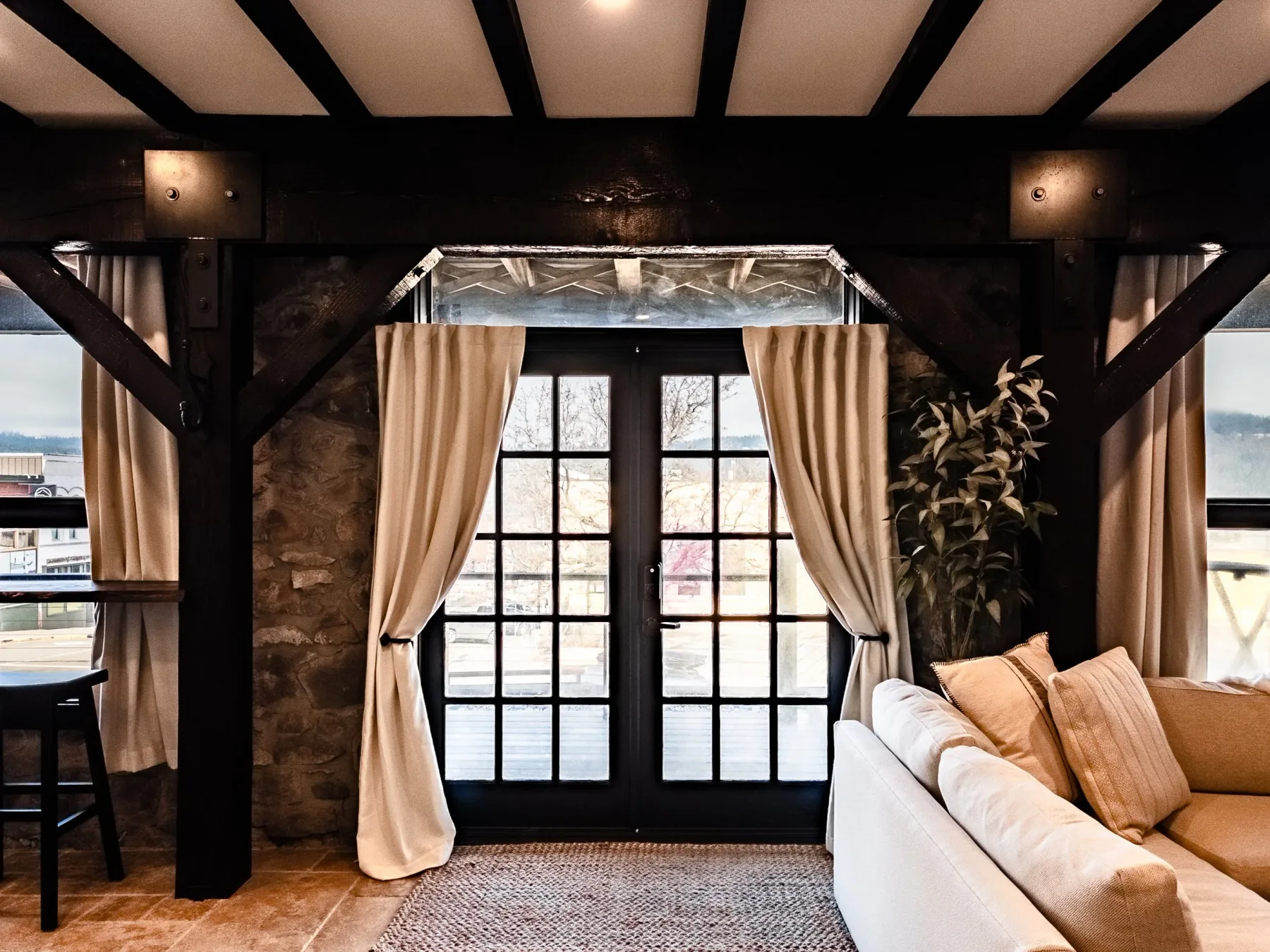 Representative hotel space: A warmly lit living room has a white seating area beside tall curtained windows.