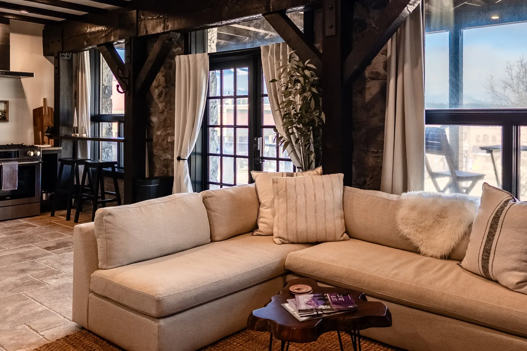 Representative hotel space: Living room with a sectional seating area beside large windows.