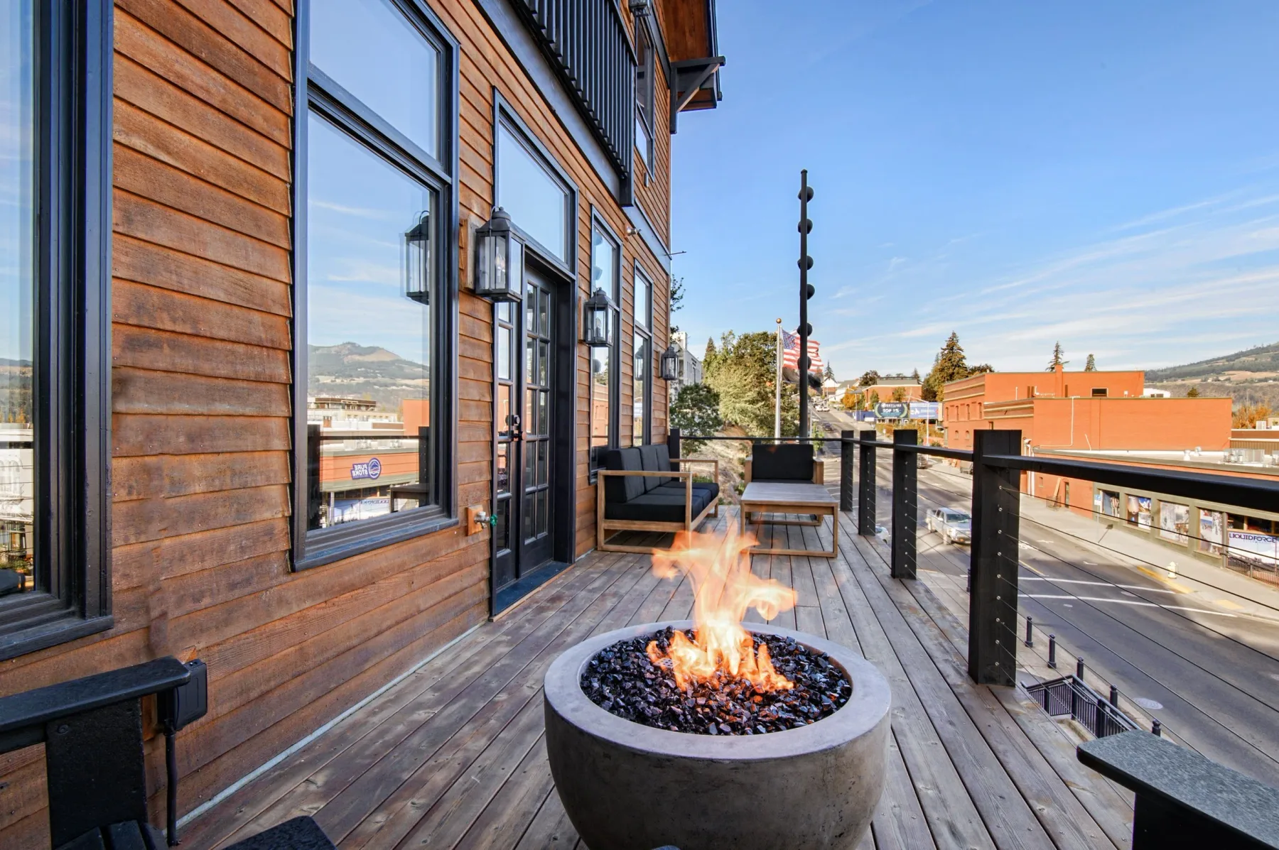 Representative hotel space: A wooden deck with a round fire pit and seating overlooks the street.