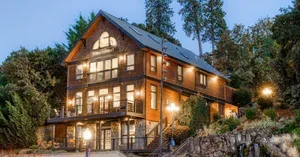 Representative hotel space: A multi-story building with illuminated windows stands among trees at dusk.